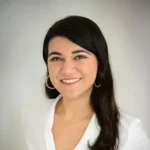 The Star Society author Gabriella Saab smiling with long dark hair, hoop earrings, white blouse.