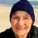 Apple & Palm stories author Patricia Henley on beach wearing a hat.