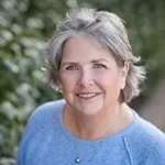 The Chambermaid's Key author Genevieve Graham smiling with gray hair outdoors.