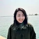 An Empire in the Clouds author Ai Jiang smiling by the water