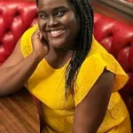 An Arcane Inheritance An Arcane Inheritance author Kamilah Cole smiling in yellow dress.