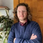 The Ship of Death The Ship of Death author Kyle Winkler with curly hair and glasses.