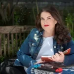 the strangers The Strangers author Naomi Alderman sitting outdoors with notebook.