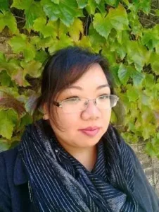 Author Shoutout Author Shoutouts Nghi Vo with glasses near greenery.
