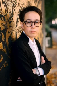Author Shoutout Author Shoutouts Aliette de Bodard in suit with glasses, serious expression