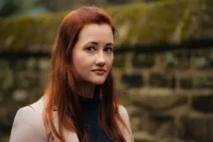 Author Shoutout Author Shoutouts Tamsyn Muir with long red hair outdoors