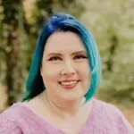 The Thorns We Wear Inside author Amy Avery with blue-green hair smiling